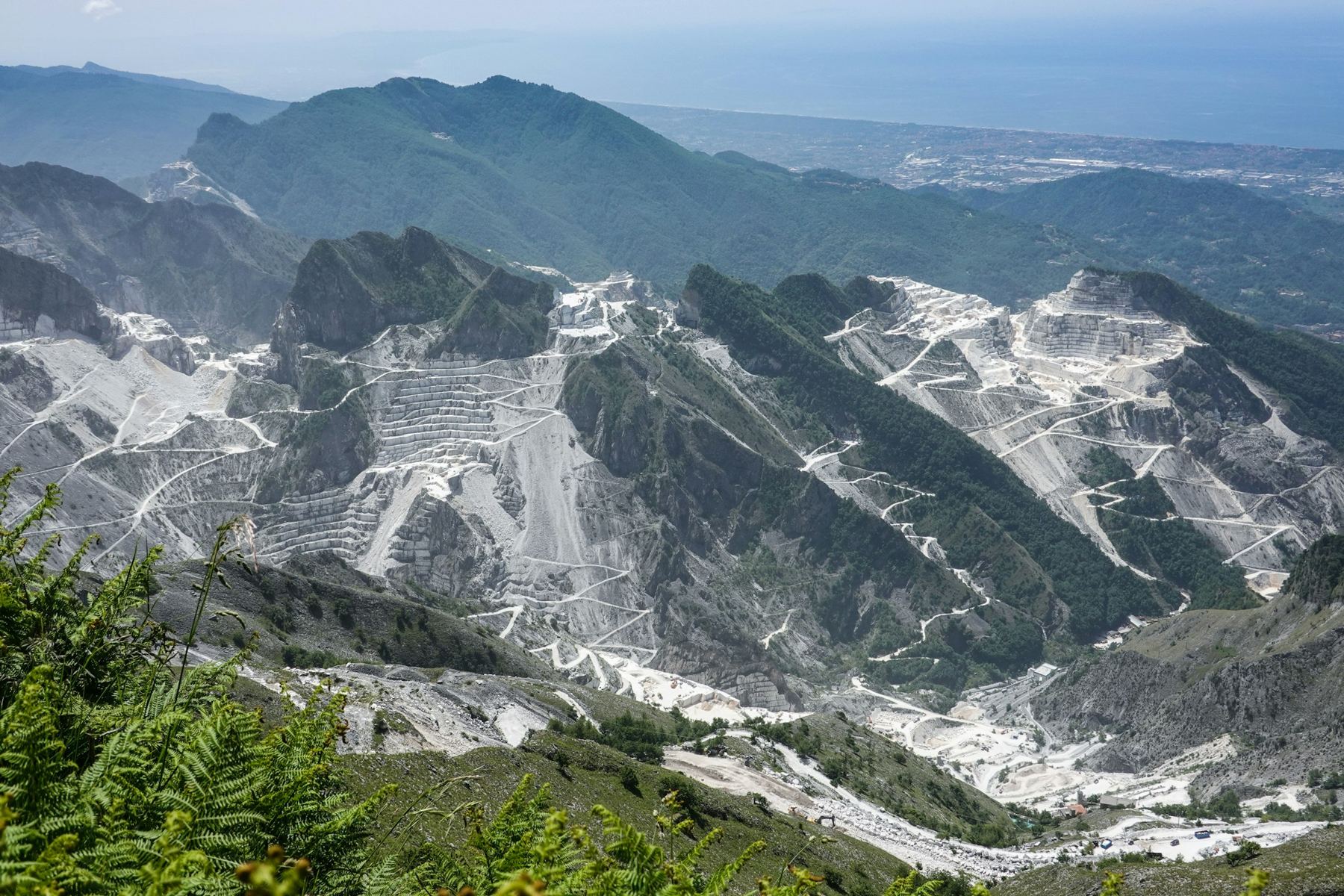 Marble quarries cut in terraces into the Apuan Alps above Carrara, with the sea beyond